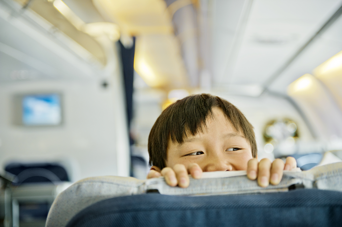 Boy looking over business class seat of plane