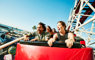 Laughing and screaming couple riding roller coaster at amusement park